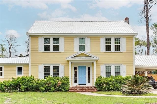 Yellow two-story home with a metal roof